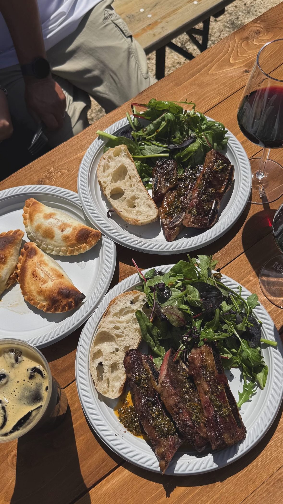 A served plate with asado, empanadas, salad and red wine at a Gauchas event